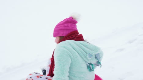 Slow-motion-shot-of-young-girl-sledding-down-a-hill-in-winter