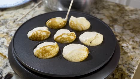 Using-a-wooden-stick-to-turn-aebleskivers-in-the-pan-so-they-cook-into-a-ball---AEBLESKIVER-SERIES