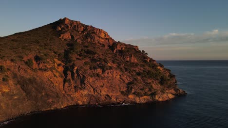 Drohnenaufnahmen-Einer-Klippe-Am-Meer-Entlang-Der-Mittelmeerküste,-Während-Sie-Wunderschön-Vom-Sonnenuntergang-Beleuchtet-Werden