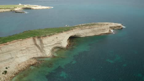 AERIAL:-Ras-il-Fniek-Point-in-Marsaxlokk-with-Majestic-Turquoise-Mediterranean-Sea-Waves-Crashing-in-Shore