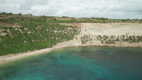 AERIAL:-Greenery-on-Slope-in-Il-Hofra-l-Kbira-Bay-with-Turquoise-Colour-Water