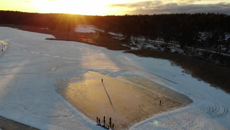 Aerial-view-of-people-playing-ice-hockey-on-a-frozen-lake-in-the-sunset
