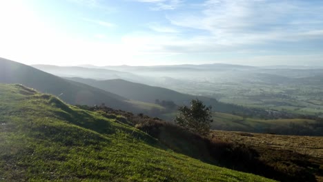 Distant-misty-layers-of-panoramic-rural-dreamlike-mountain-valley-countryside-at-sunrise-locked-off-shot