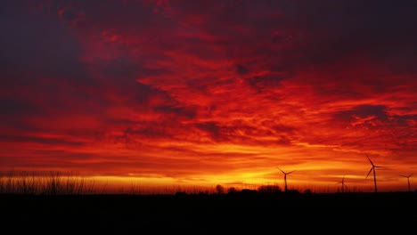 Wind-park-turbines-timelapse-during-a-red-and-orange-dramatic-sky-landscape-while-generating-eolic-energy