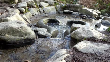 River-flowing-through-primitive-weathered-eroded-smooth-stone-worn-basin-low-angle