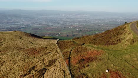 Early-sunlight-on-highland-mountain-peak-aerial-view-across-vast-North-Wales-frosty-idyllic-farmland-countryside-orbit-left