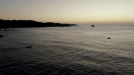 Silhouette-Of-Boat-On-Sea-During-Sunset-In-Mazunte,-Mexico---aerial-drone-shot