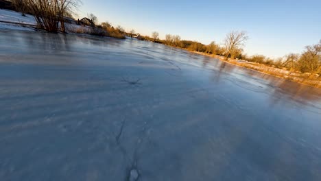Drone-Rápido-Volando-Sobre-Un-Estanque-Congelado-En-Michigan-Durante-La-Puesta-De-Sol