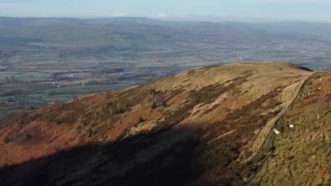 Early-sunlight-on-highland-mountain-peak-aerial-view-across-vast-frosty-idyllic-Denbighshire-farmland-countryside