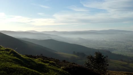 Distant-misty-dreamlike-layers-of-panoramic-rural-mountain-valley-peaks-countryside-at-sunrise