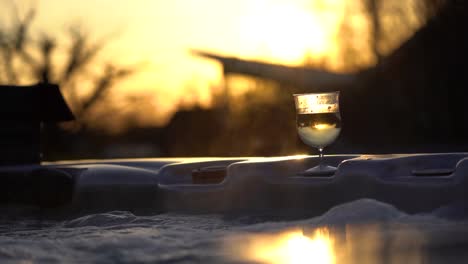 Close-up-of-a-glass-of-sparkling-wine-in-a-jacuzzi-during-sunset