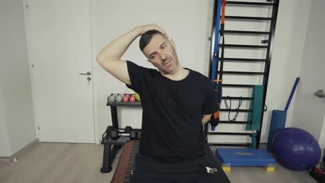 A-man-stretches-his-neck-muscles-before-a-workout-at-his-small-home-gym
