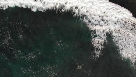 Aerial-view-of-big-waves-coming-from-the-ocean-in-Uluwatu,-Bali