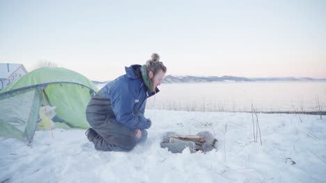 Guy-Blowing-Hard-Firewood-On-The-Campfire-During-Camping-Trip-At-Wintertime