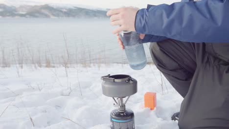 Mann-Gießt-Wasser-Auf-Teekanne-über-Tragbaren-Campingkocher