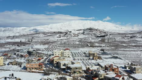 Houses-in-the-city-of-Buqata-with-snow-on-the-roofs-on-a-cleared-road-with-in-the-background-Hermon-mountain-on-a-bright-sunny-day