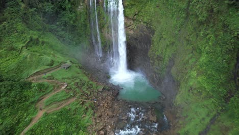 Aerial-dolly-out-of-Eco-Chontales-waterfall-streaming-into-turquoise-rocky-pond-surrounded-by-dense-rain-forest,-Costa-Rica