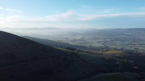 Distant-misty-layers-of-panoramic-rural-mountain-North-Wales-valley-countryside-at-sunrise-aerial-view-slow-pan-right