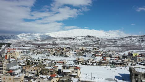 Casas-Y-Campos-Cubiertos-De-Nieve-Mientras-Las-Sombras-Se-Mueven-Lentamente-Sobre-La-Montaña-Hermon-En-El-Fondo