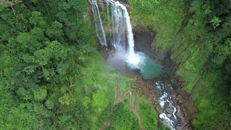 Aerial-lowering-over-Eco-Chontales-waterfall-streaming-into-turquoise-rocky-pond-surrounded-by-tropical-jungle,-Costa-Rica