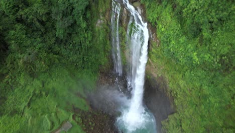 Aerial-dolly-out-of-Eco-Chontales-waterfall-falling-down-high-cliff-into-turquoise-pond-surrounded-by-dense-jungle,-Costa-Rica