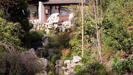 Nahaufnahme-Eines-Friedlichen-Wasserfalls-Und-Baches-In-Einem-Botanischen-Garten-Außerhalb-Eines-Chinesischen-Tempels