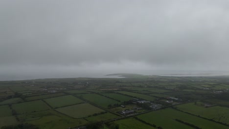 Drone-shot-of-Irish-countryside-on-a-cloudy-day-with-the-ocean-in-the-background