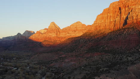 Orange-sunlight-falling-on-vertical-rocky-canyons-of-Springdale,-Zion-national-park