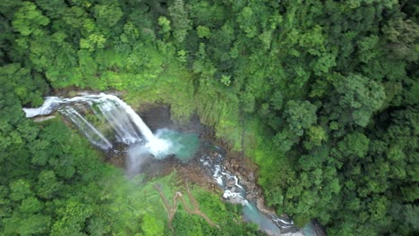 Aerial-orbit-of-Eco-Chontales-waterfall-falling-down-natural-pond-surrounded-by-dense-green-tropical-woodland,-Costa-Rica