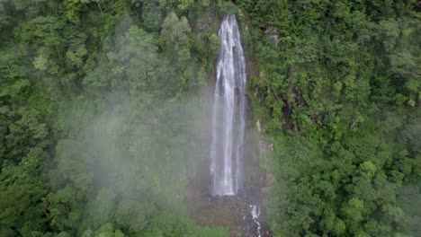 Aerial-pan-right-of-Las-Lajas-waterfall-streaming-in-high-cliff-surrounded-by-dense-woods,-San-Luis-Morete,-Costa-Rica