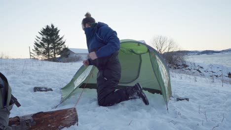 Man-Assembling-Tent-On-Snowy-Ground-At-Wintertime-In-Norway