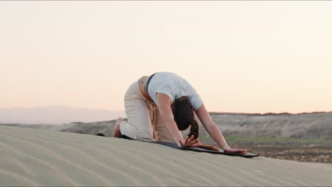 Junge-Brünette-Yogalehrerin-Wärmt-Sich-Im-Sand-Auf