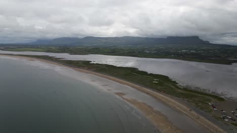 Drone-shot-of-a-beach-with-mountains-in-the-background-in-Ireland