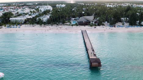 Wooden-pier-on-beach-in-front-of-tropical-resort-area