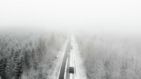 Aerial-view-of-a-car-driving-in-the-snow-during-Winter