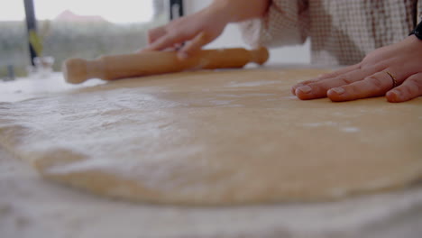 Young-Female-roll-out-dough-for-a-cake-in-the-kitchen-at-home