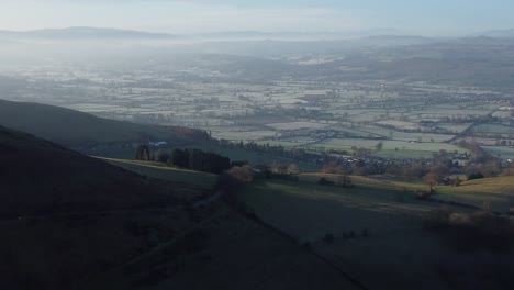 Distant-misty-layers-of-panoramic-rural-mountain-valley-countryside-at-sunrise-aerial-view-slow-orbit-right