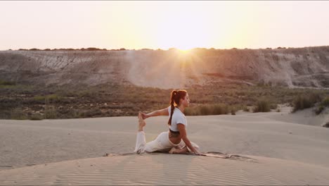 Junge-Brünette-Yogalehrerin,-Die-Bei-Sonnenaufgang-Im-Sand-Auftritt