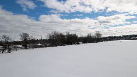 Man-Ice-fishing-on-a-frozen-Lake-in-Muskegon,-MI