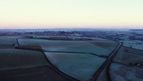 A-road-leading-towards-an-English-countryside-village-on-a-cold-frosty-winters-morning