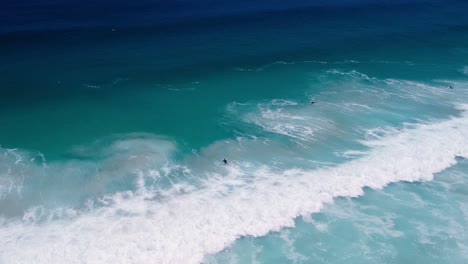 Surfer-duck-diving-under-a-wave,-distant-drone-shot