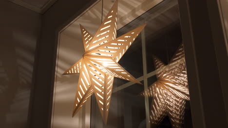 Decorative-Advent-star-hangs-by-window-at-night,-slow-pan-from-below