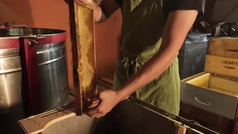 Nahaufnahme-Des-Imkers,-Der-Bienenwachs-Aus-Rahmen-Entfernt,-Honigproduktionsindustrie
