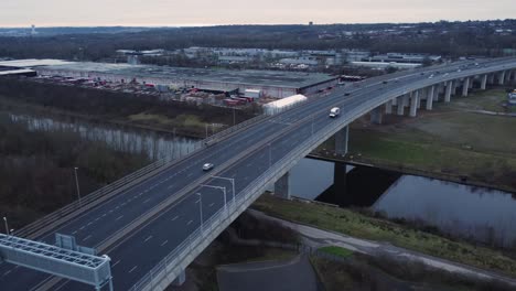 Mersey-gateway-toll-bridge-highway-traffic-driving-across-river-estuary-aerial-view-high-tilt-down-pan-left
