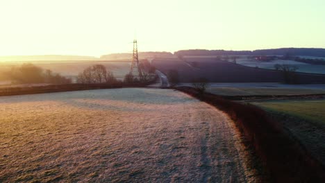 Frosty-winter-sunrise-over-farmers-fields-with-a-pilon-and-a-road