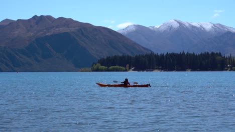 A-woman-kayaking-in-Lake-Wanaka,-New-Zealand-on-a-sunny-day