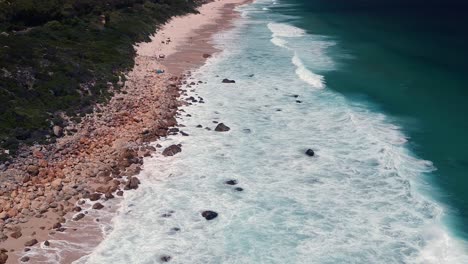 Crashing-waves-on-shoreline-with-rocks,-wide-drone-shot