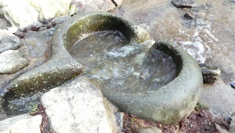 River-flowing-through-primitive-weathered-eroded-smooth-stone-worn-basin-handheld-shot