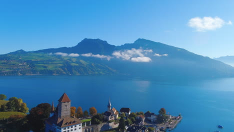 Satisfying-drone-flyover-of-picturesque-lake-near-medieval-Church-in-Spiez,-Switerzland-in-the-summer,-noon,-wide-view,-europe