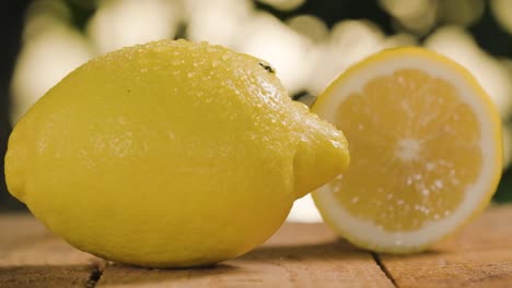 Zitronen-Auf-Holztisch,-Wassertropfen,-Die-Von-Frischer-Zitrone-Fallen,-Bokeh-Hintergrund